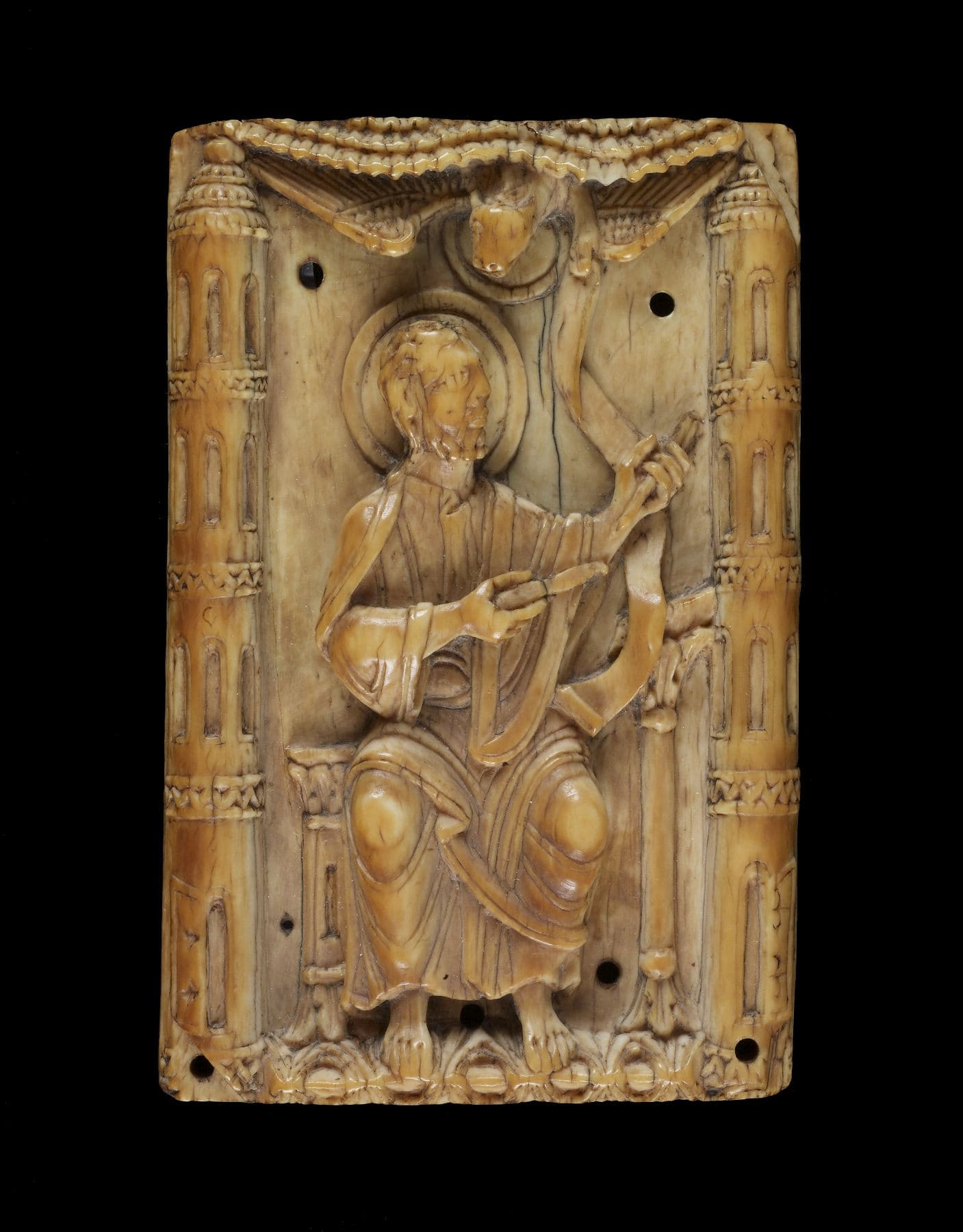 Ivory carving of Saint Luke seated at a lectern, with a winged ox above him, from an eleventh-century Gospel book cover.