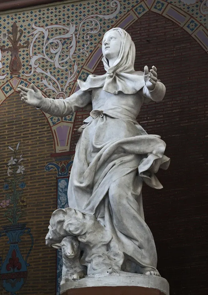 Germaine Cousin: stone statue of a woman holding a shepherd's crook, with a sheep beside her