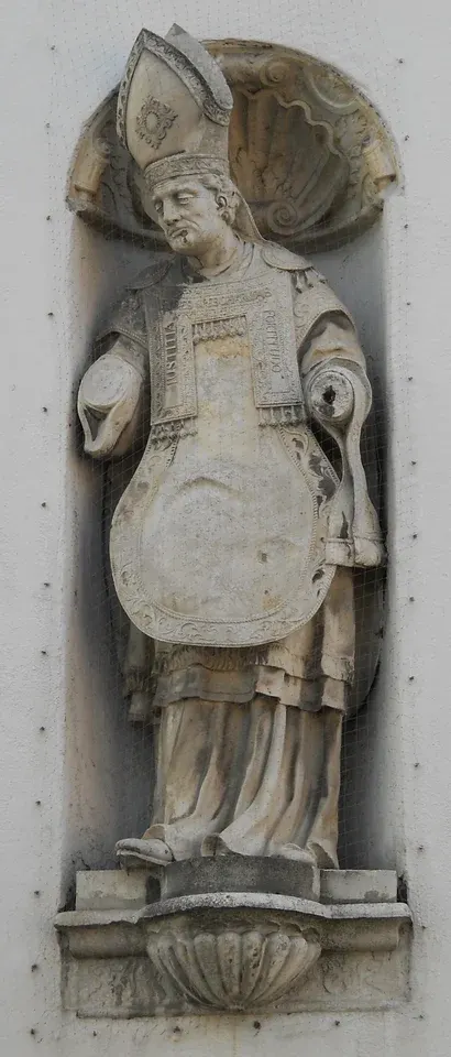Willibald: weathered stone statue of a bishop in a wall niche