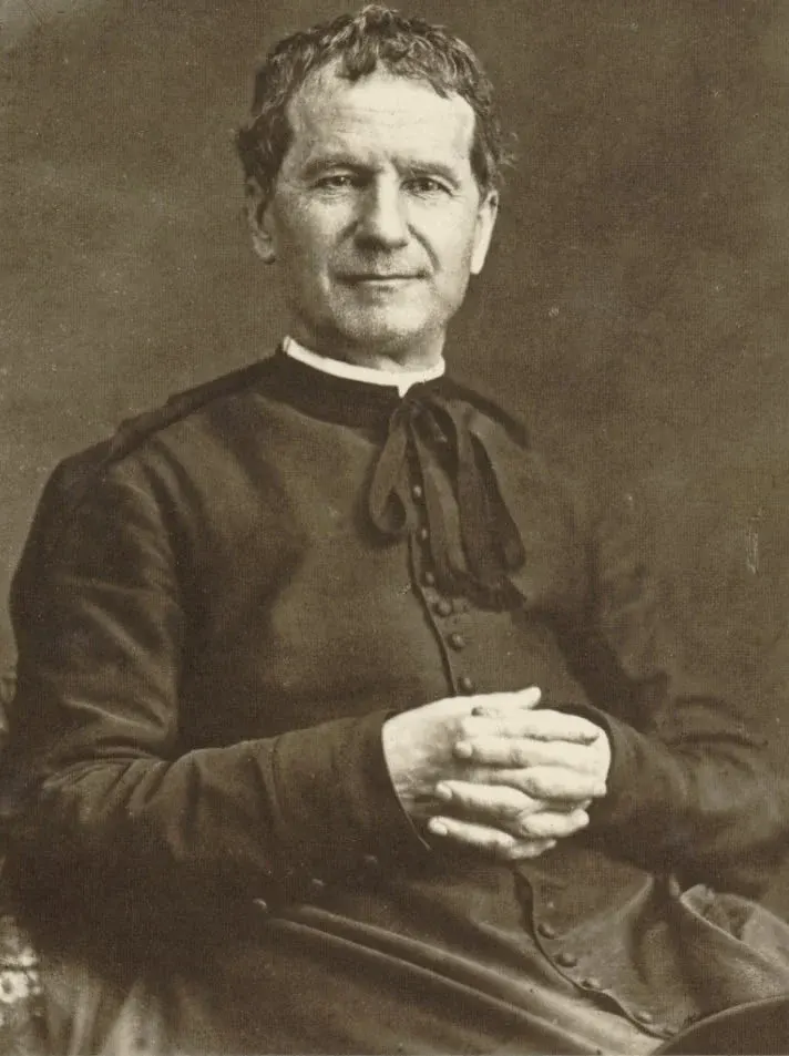 John Bosco: sepia photograph of a seated priest with hands together